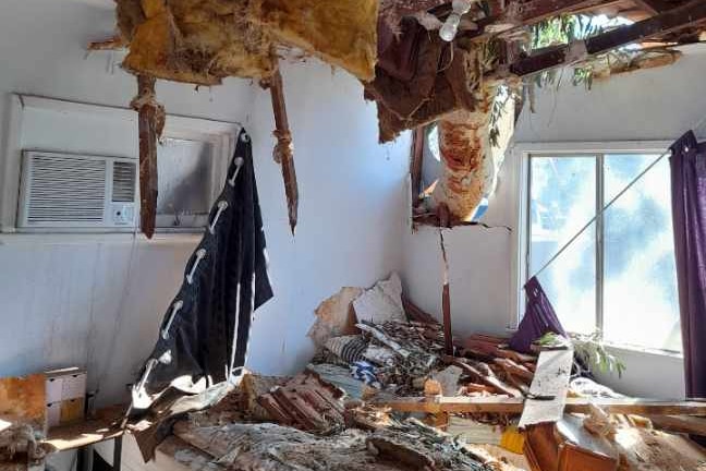 Interior of a house where the ceiling has collapsed and insulation in the roof is exposed.