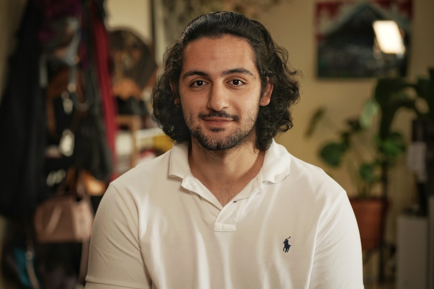 A man with medium length hair smiles at camera.