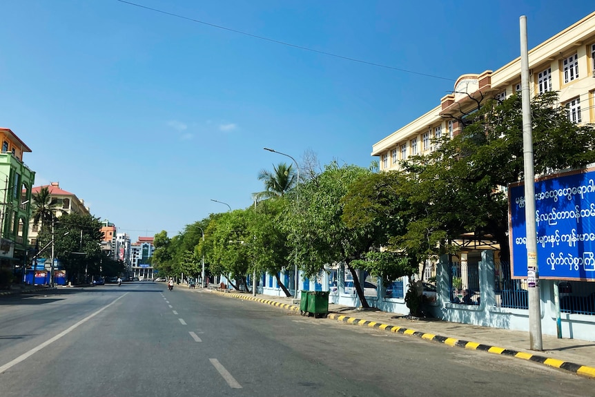 An empty city street on a cloudless sunny day in Mandalay.