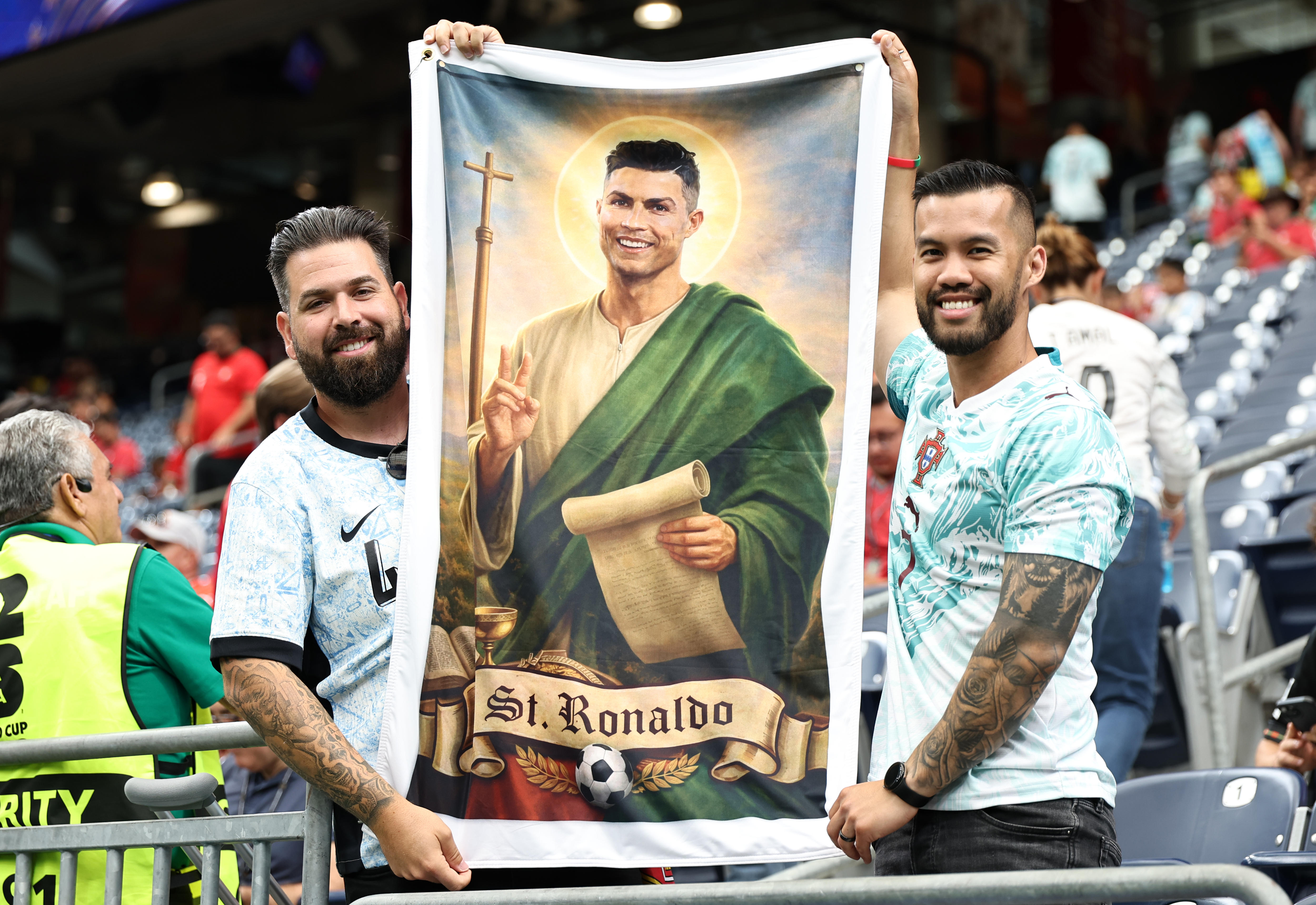 Two Portugal fans inside the stadium hold a banner which depicts Cristiano Ronaldo as a saint