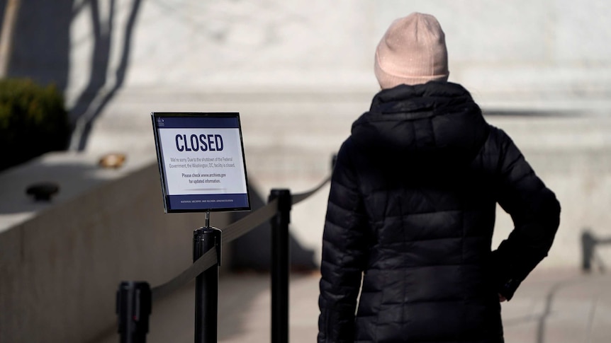 A woman looks at a sign declaring the National Archive is closed
