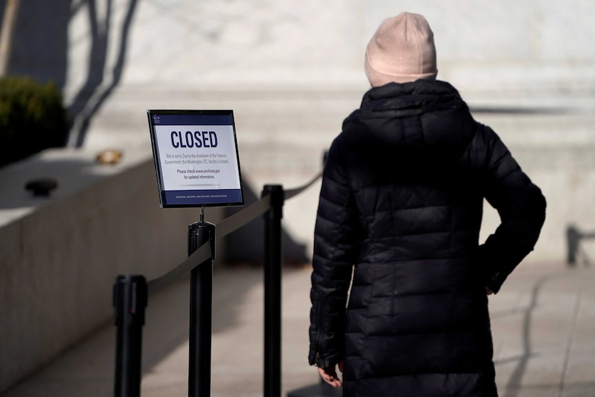 A woman looks at a sign declaring the National Archive is closed