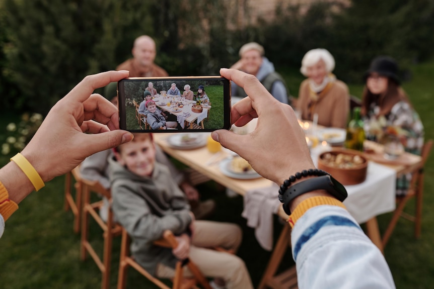 A person taking a photo on their smartphone of a happy family gathering