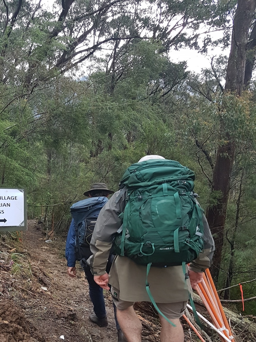 Two hikers next to a sign labelled "Bogong Village pedestrian access"