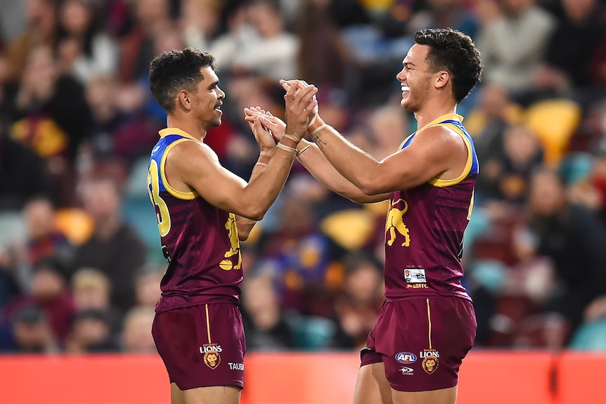 Two men celebrate a goal in an AFL match