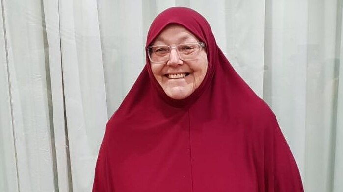 A woman in a red hijab smiles for the camera