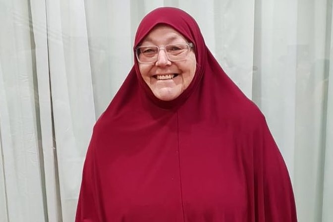 A woman in a red hijab smiles for the camera