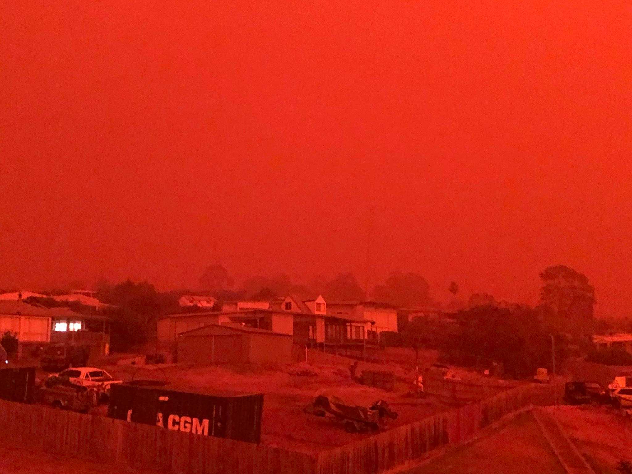 A bright red sky can be seen over houses.