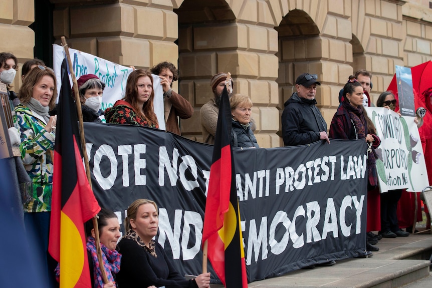 People hold protest signs outside Tasmania's parliament