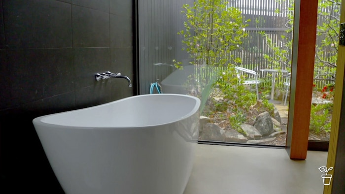 Spacious bathtub with window showing a courtyard garden outside.