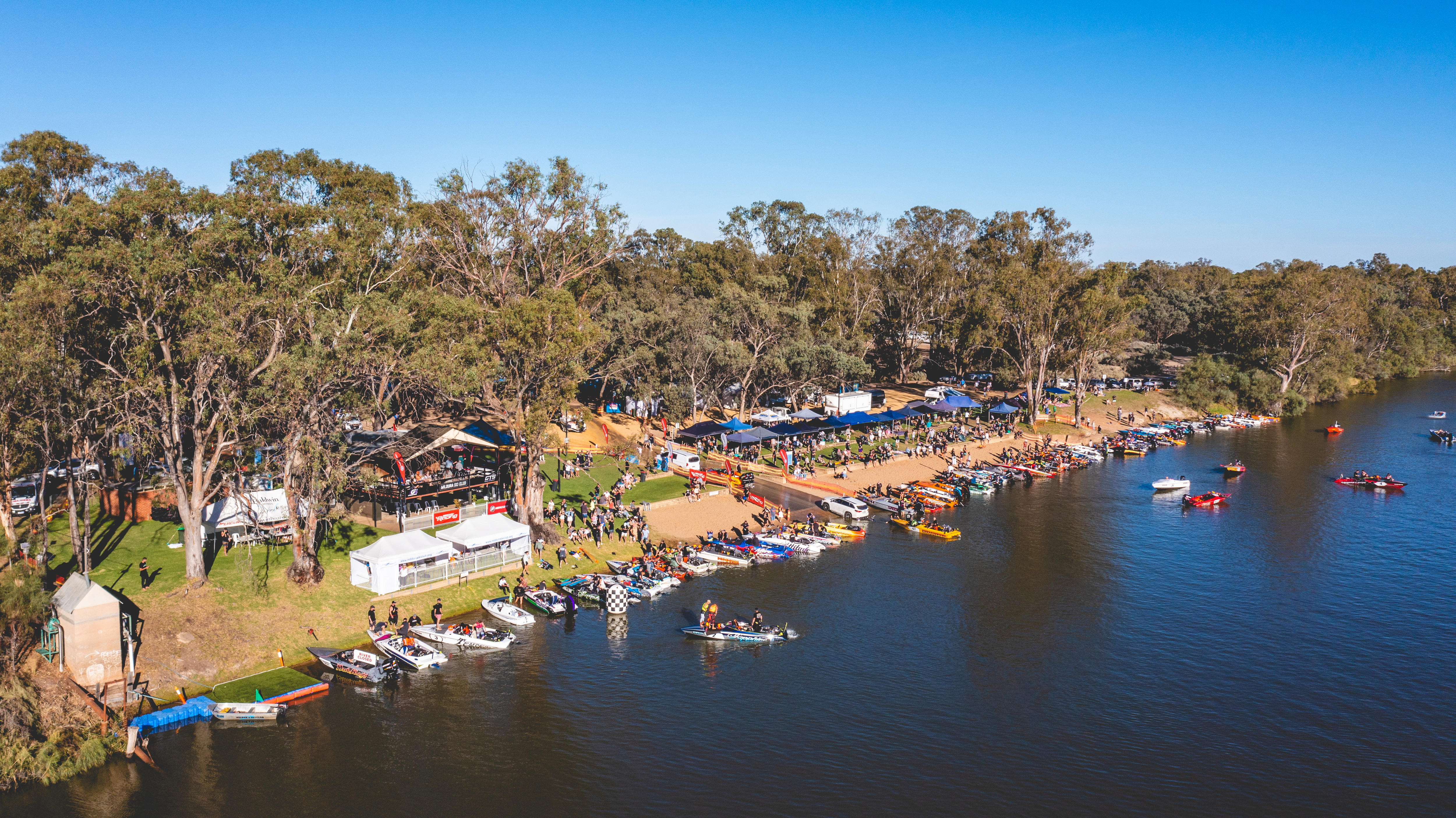 Un río con árboles mallee, un banco de arena y decenas de esquiadores y personas.