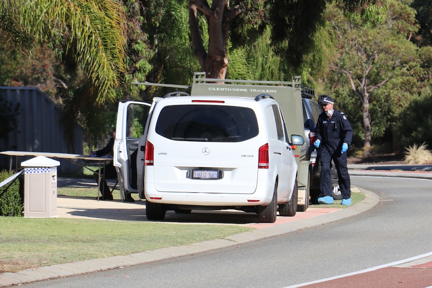 A white van behind a 4WD with a trailer on a residential street, with a police forensics officer walking beside the vehicles.