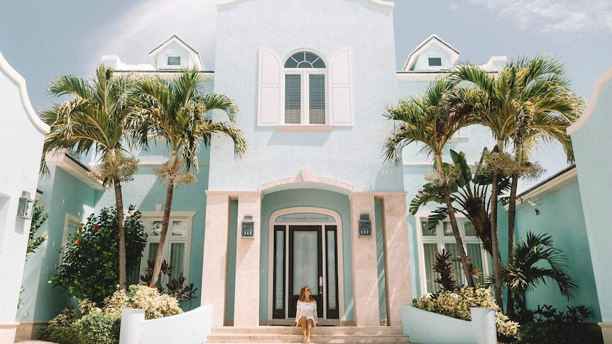 A woman in front of beautiful house for a story on the difference between good and bad debt.