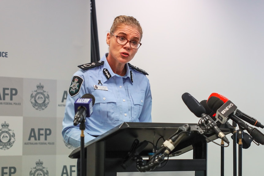 a police woman standing behind a podium with microphones speaking