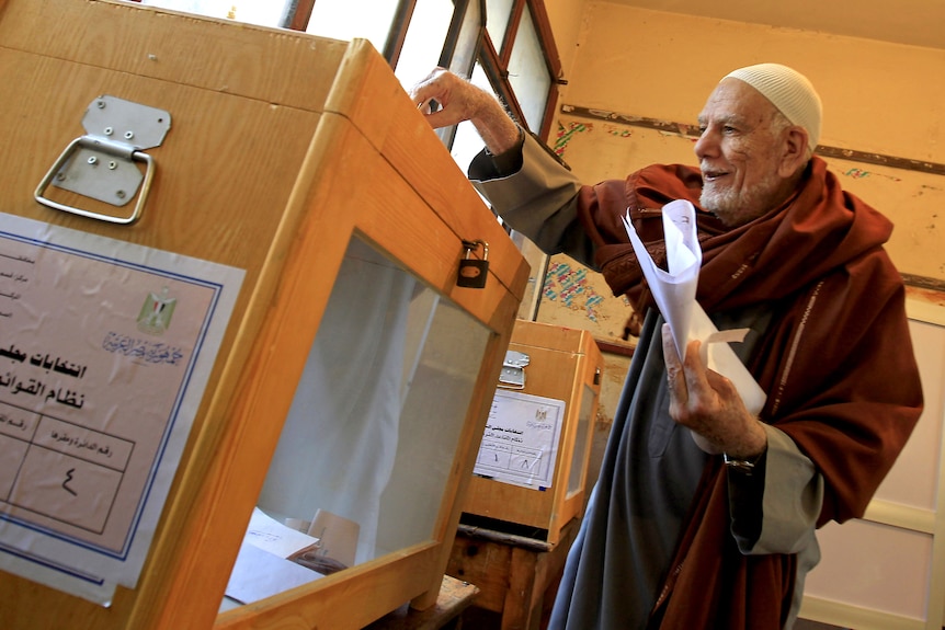 Old Egyptian man places ballot in box