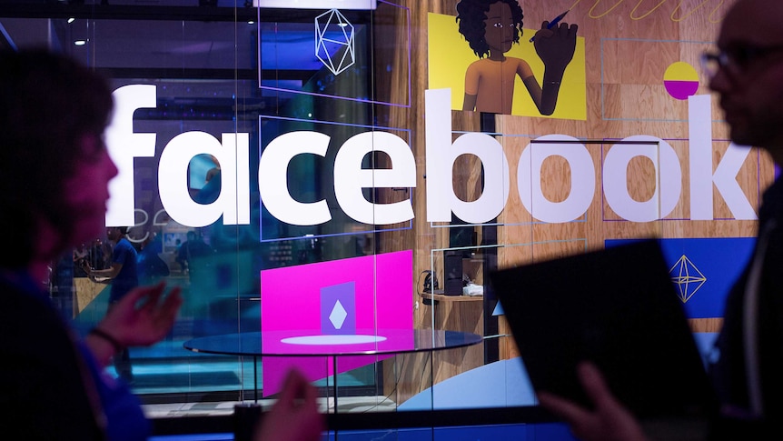 Conference workers speak in front of a demo booth at Facebook's annual F8 developer conference.