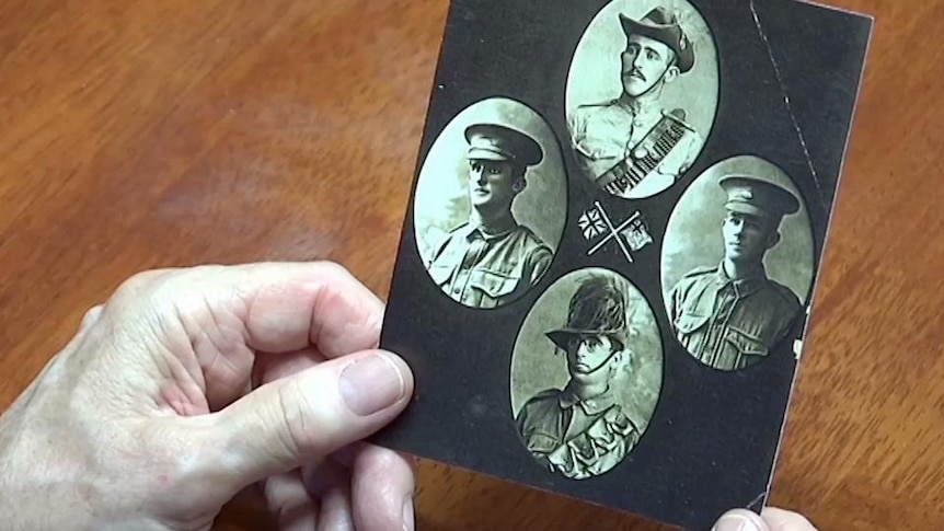 Hands hold photo of four soldiers in uniform