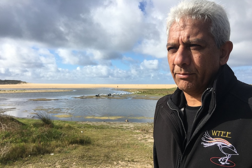 Indigenous man stands on the shore of Lake Tyers