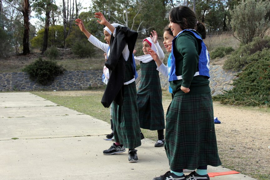 Young school students practise their defence skills on a netball court.