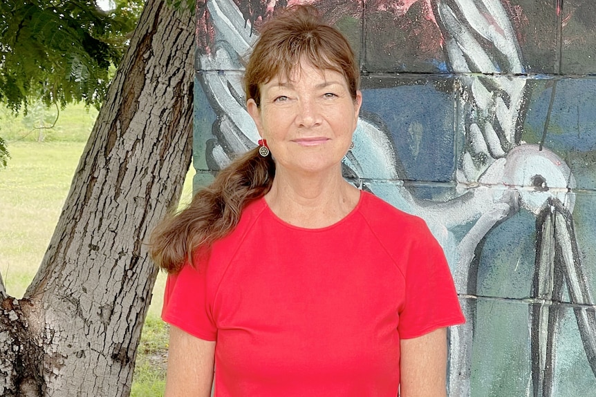 Woman in red shirt stands infront of colorful wall