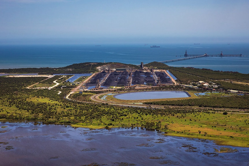 A coal storage area and dam beside a coastal wetland.