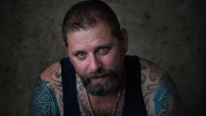 A tough-looking tattooed man with tears in his eyes.