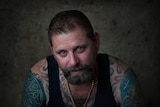 A tough-looking tattooed man with tears in his eyes.