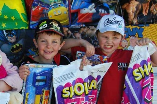 Two smiling boys holding up show bags