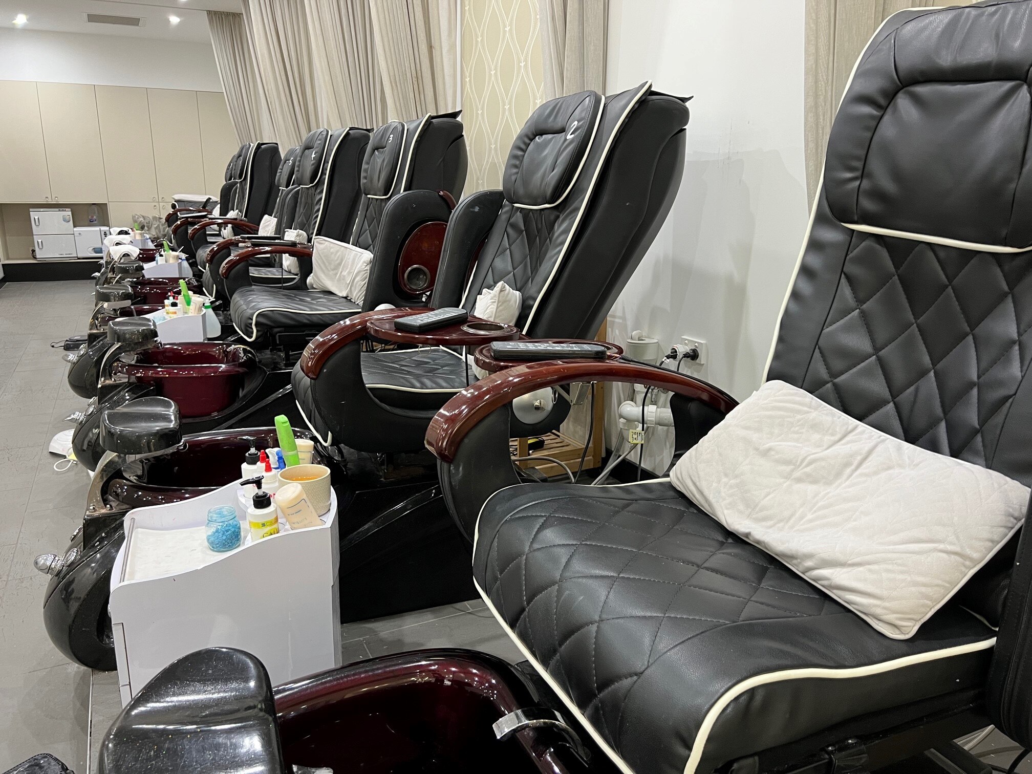 A line of black pedicure chairs sit idle in a Gold Coast salon