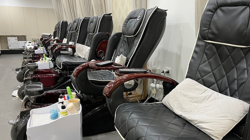 A line of black pedicure chairs sit idle in a Gold Coast salon
