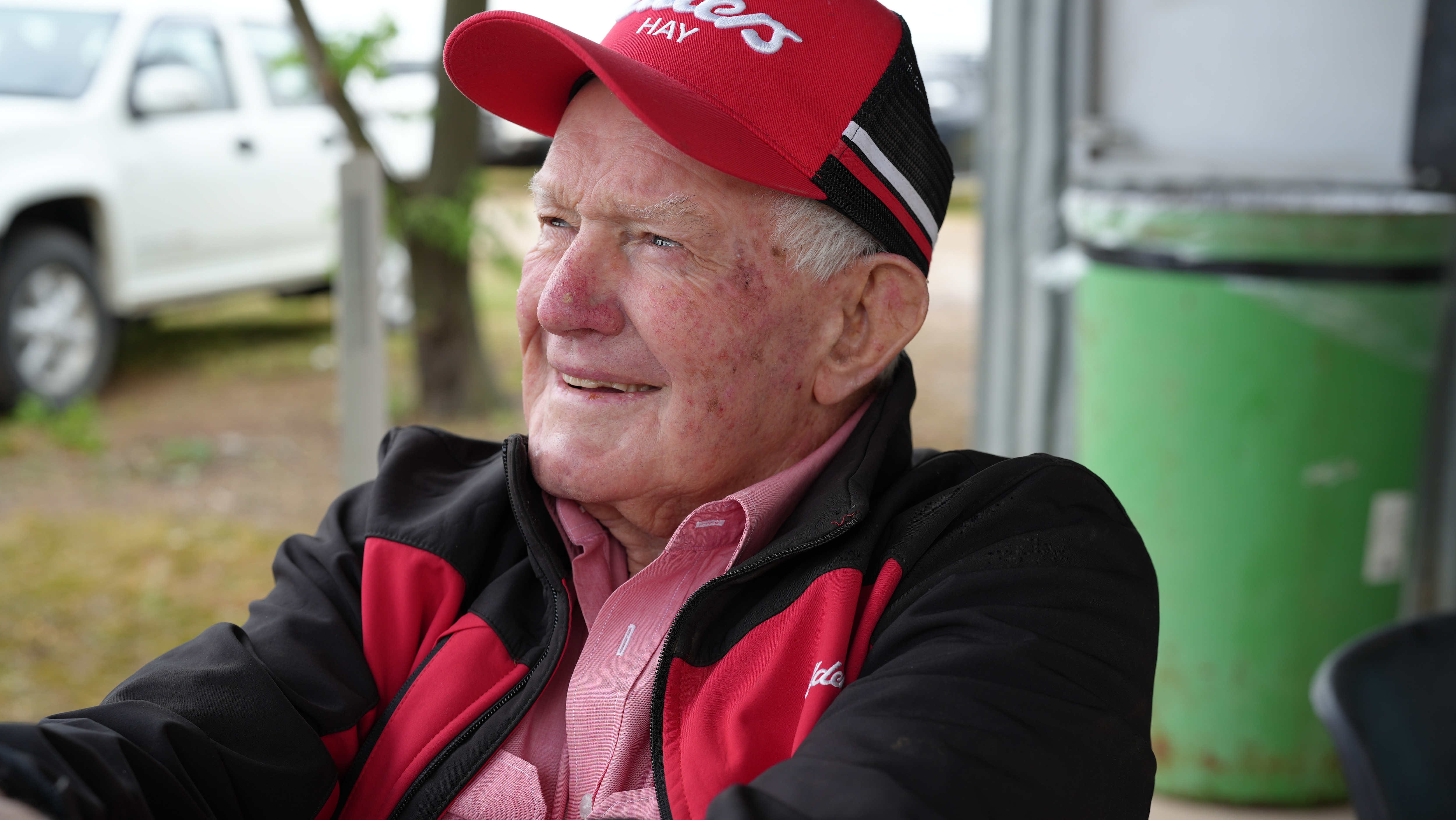 An elderly man with a red hat looking off in the distance