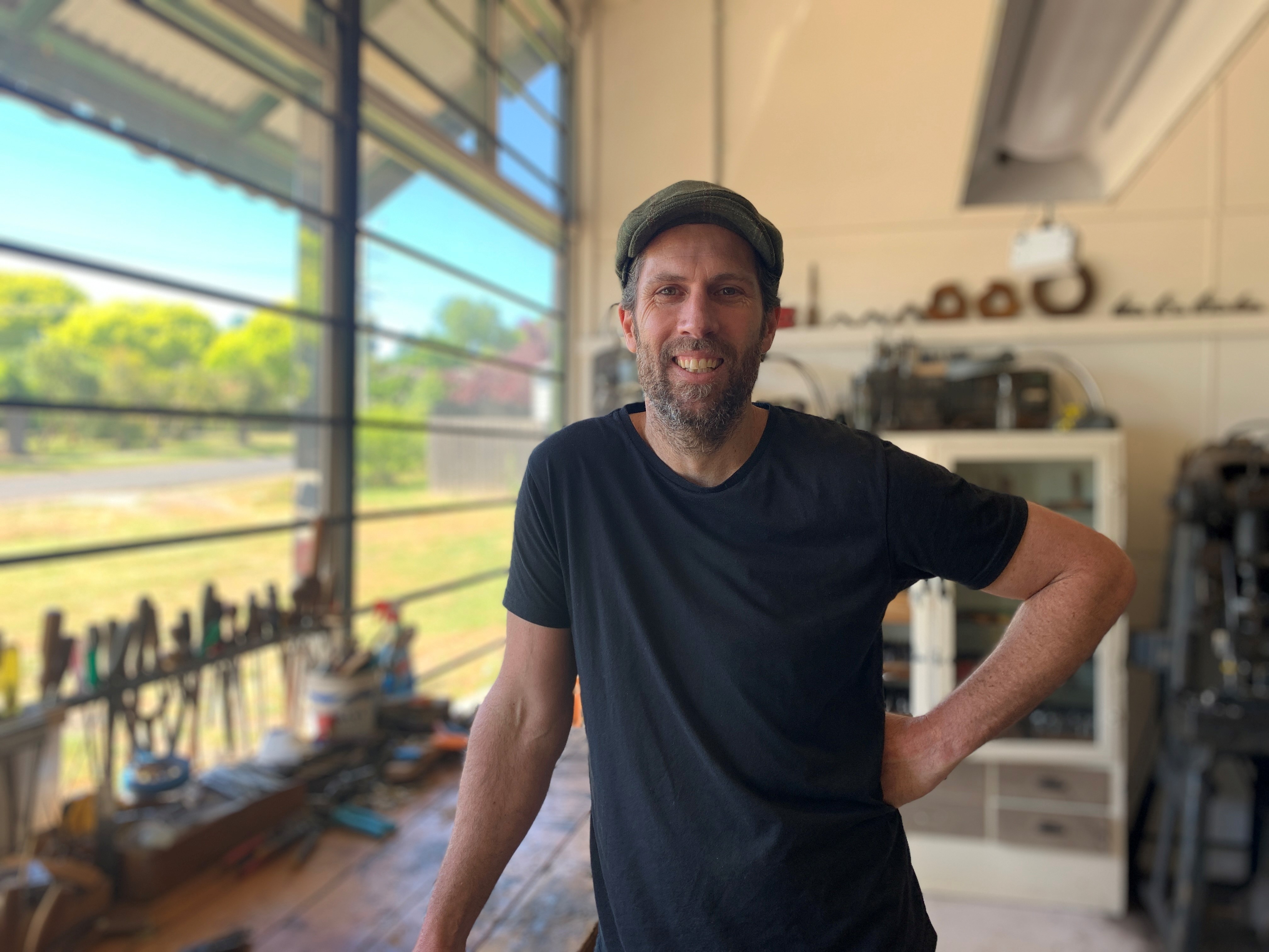 Peter Trott standing in his workshop, leaning on a bench.