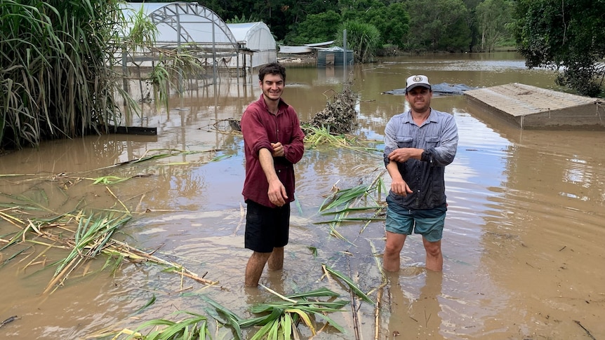 Photo of two men standing in flood waters.