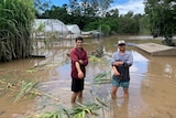 Photo of two men standing in flood waters.