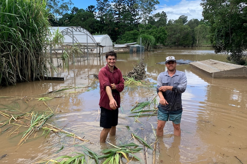 Photo of two men standing in flood waters.