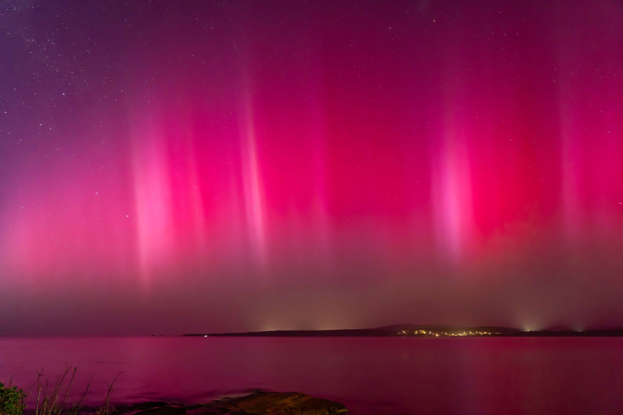 A pink and red aurora in the night sky