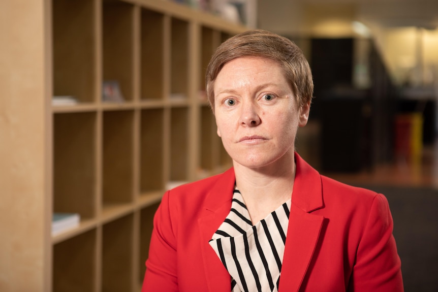 A woman wearing a red jacket looks at the camera 