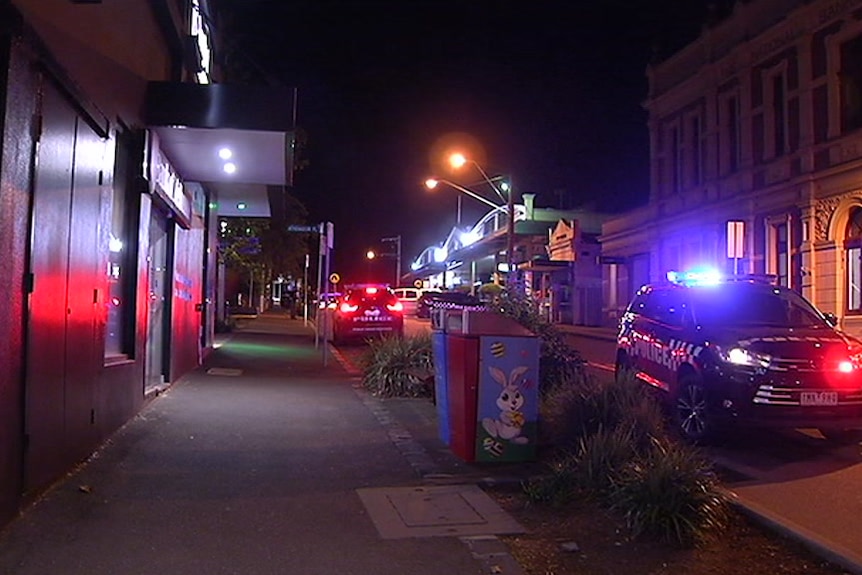 Two police cars on a street at night-time.