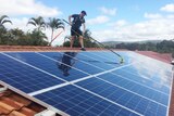 A worker from Katherine Solar NT cleans panels on a roof.