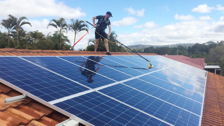 A worker from Katherine Solar NT cleans panels on a roof.