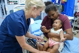 Baby and mother being talked to by a female doctor.