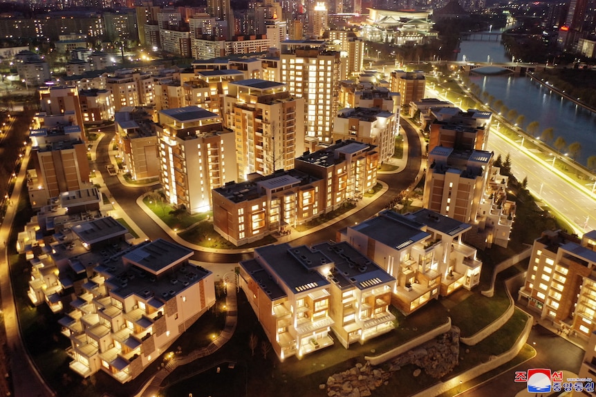 an aerial view of a residential district at night with gold lights illuminating the buildings