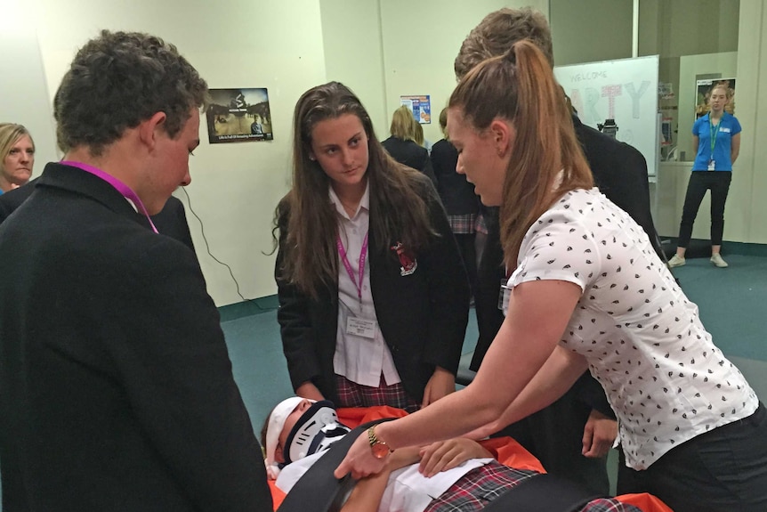 Teenagers are shown the tilt table station which is used to restrict movement after spinal injuries.