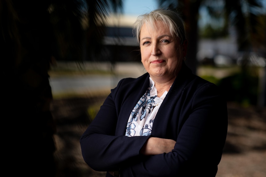 A woman with grey hair wearing a black jacket and white top