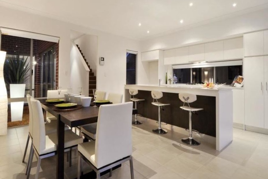 Stools sit at a kitchen bench inside an open-plan living space.