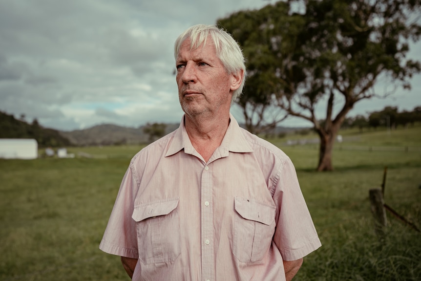 A man with a pink shirt looking at the sky.