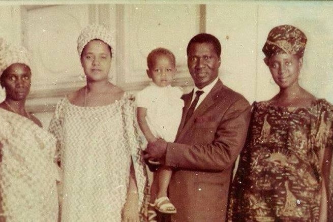 An old family photo showing a man holding a baby standing beside three other women.