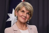 Bishop is smiling in front of an Australian flag.
