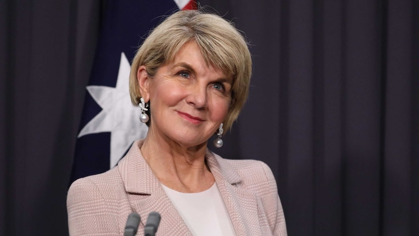 Bishop is smiling in front of an Australian flag.