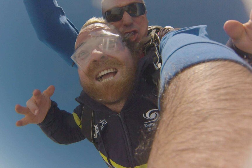 Man with beard skydiving with instructor.